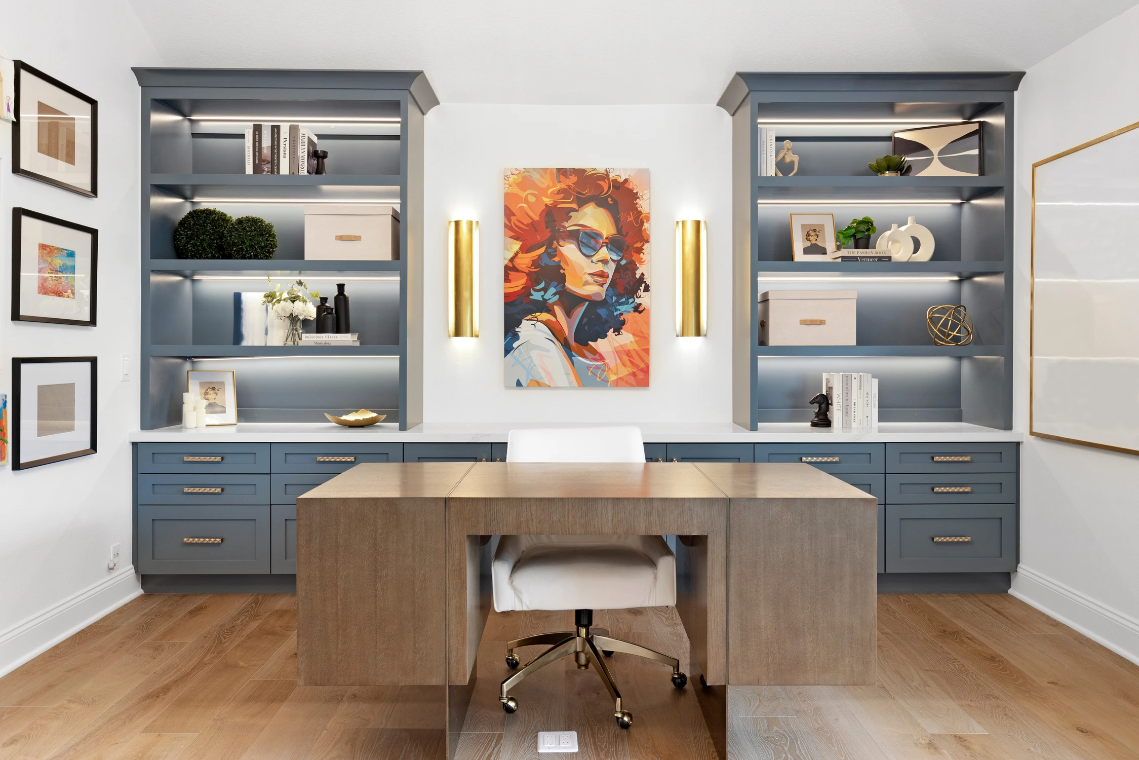 Home office with blue built-ins and colorful portrait artwork