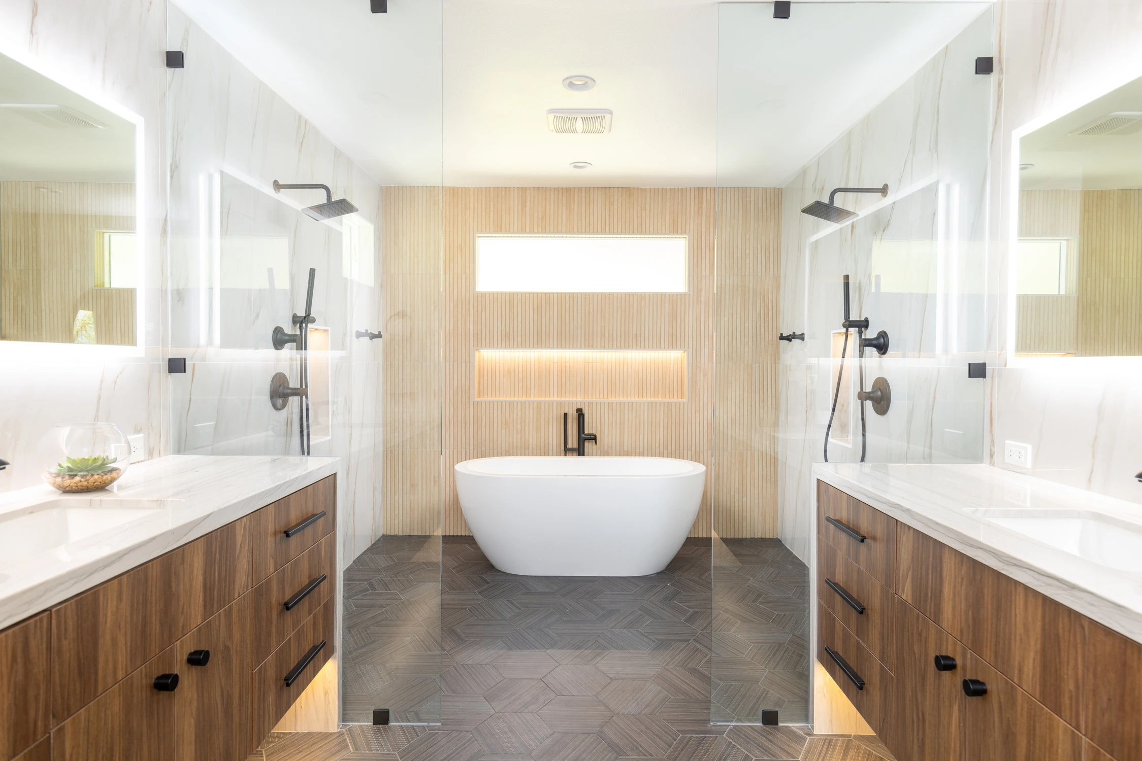 Master bathroom with freestanding tub, warm wood vanity, and pale stone walls