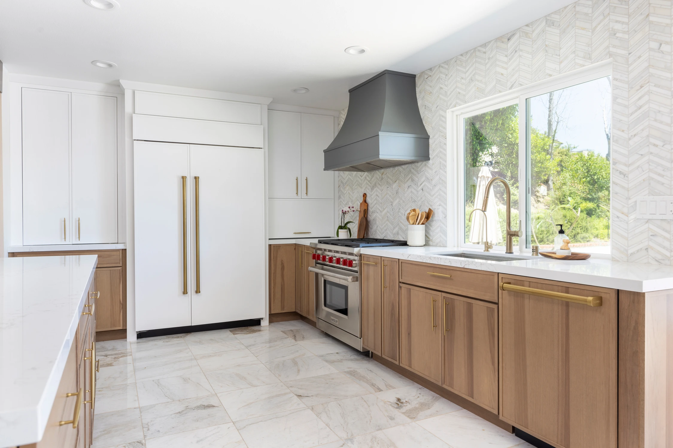 White kitchen with wood cabinetry, dark range hood, and herringbone tile