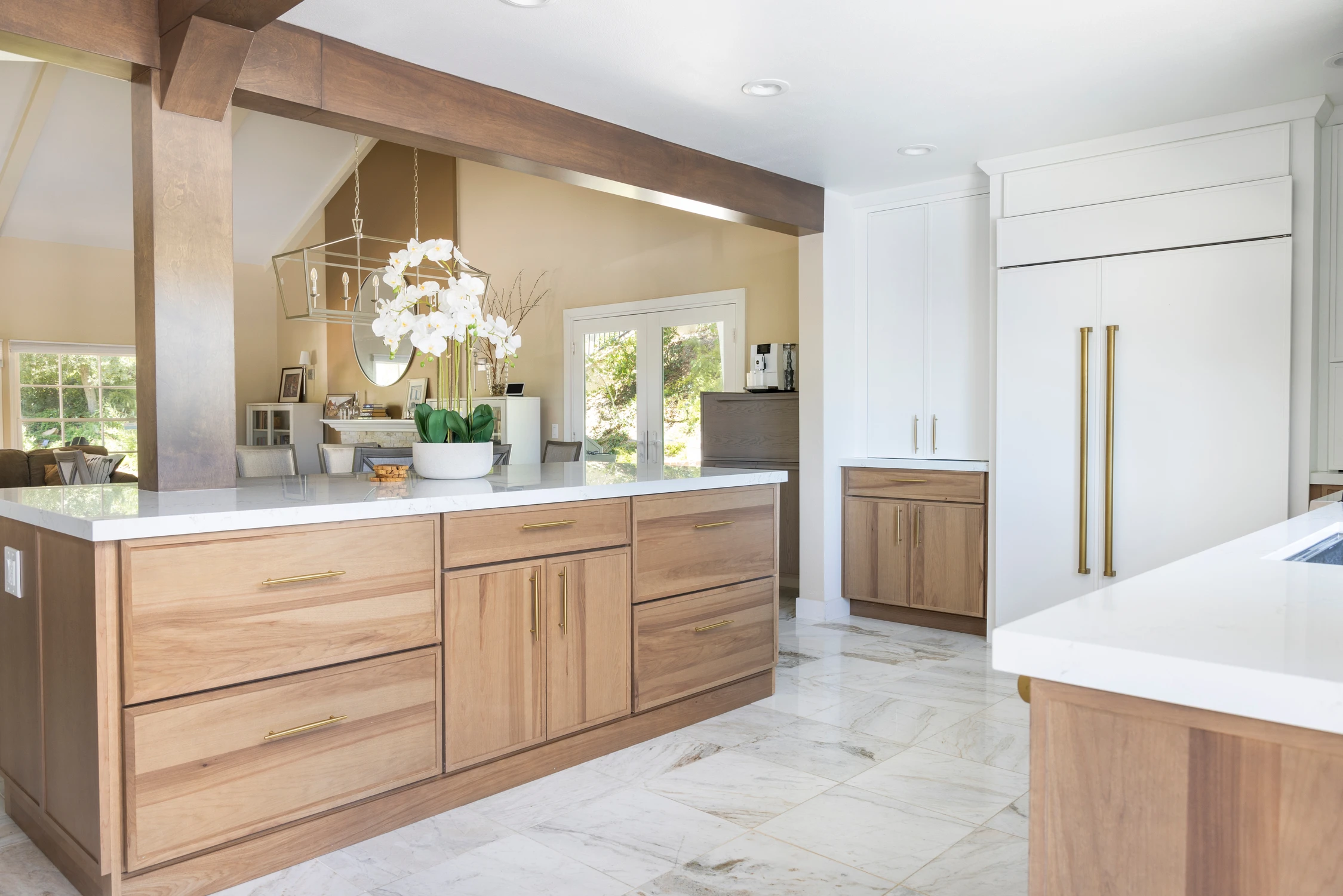 Kitchen island with wood drawers, white counter, and view toward adjoining rooms