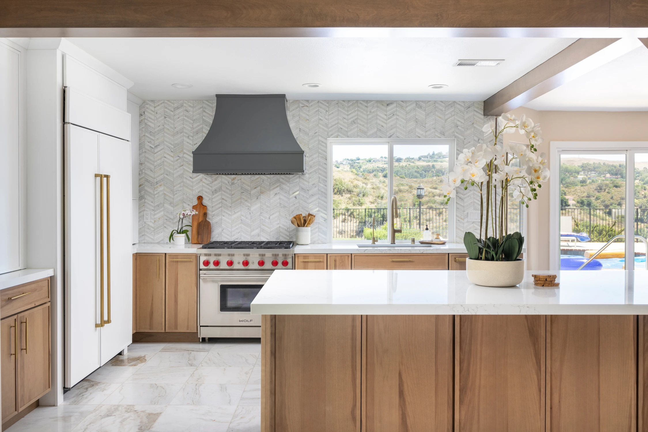 Kitchen with white island, dark hood, and window view above the range