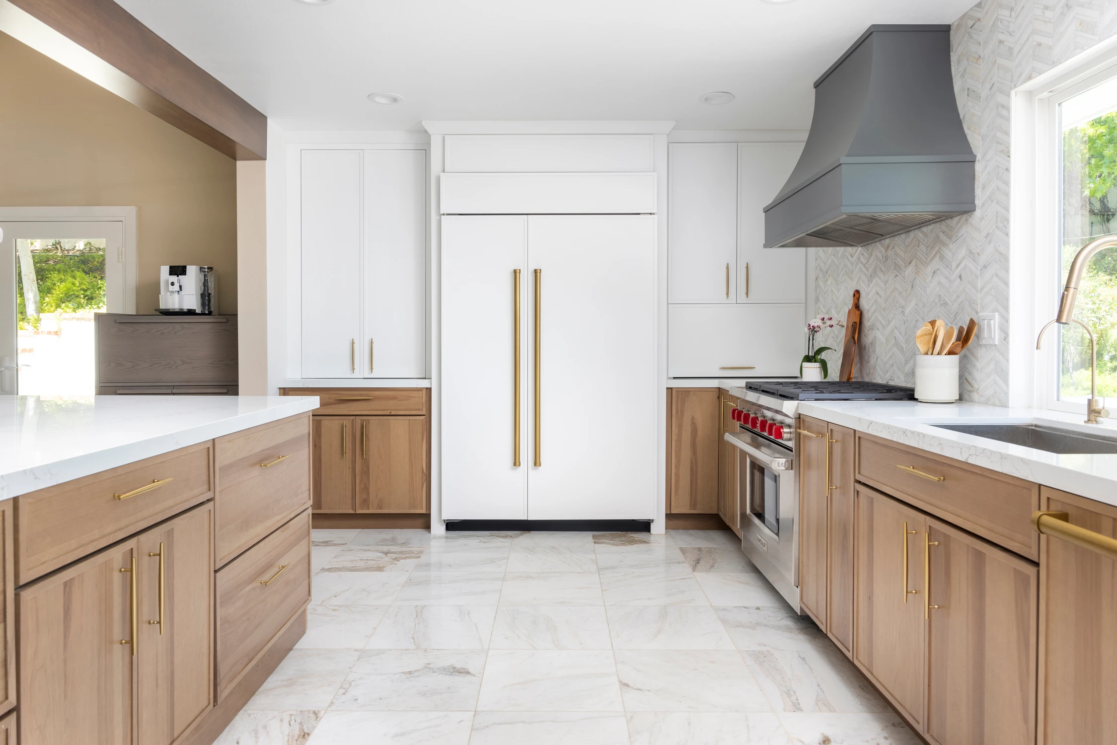 Kitchen with white refrigerator surround, wood base cabinets, and marble floor