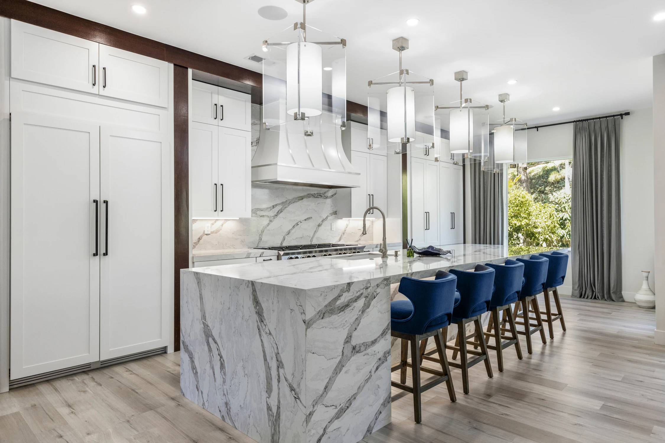 White kitchen island with blue stools and dark wood ceiling trim
