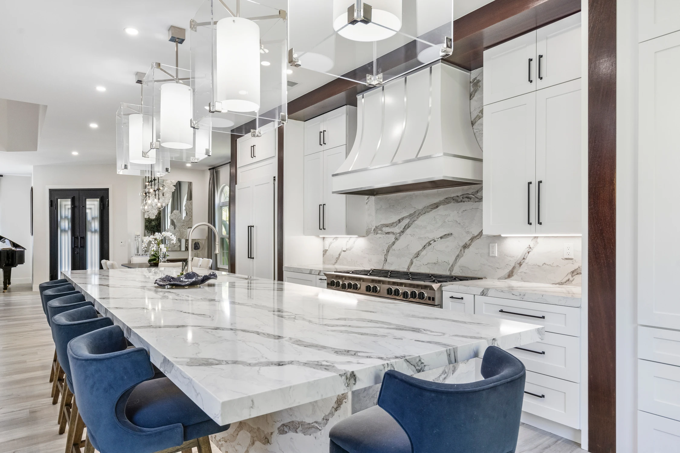 Kitchen island seating beneath glass pendants and marble-look backsplash