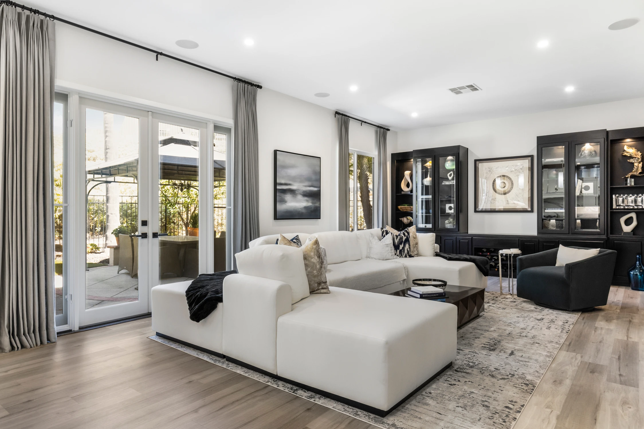 Family room with white sectional, black display cabinets, and dark chairs