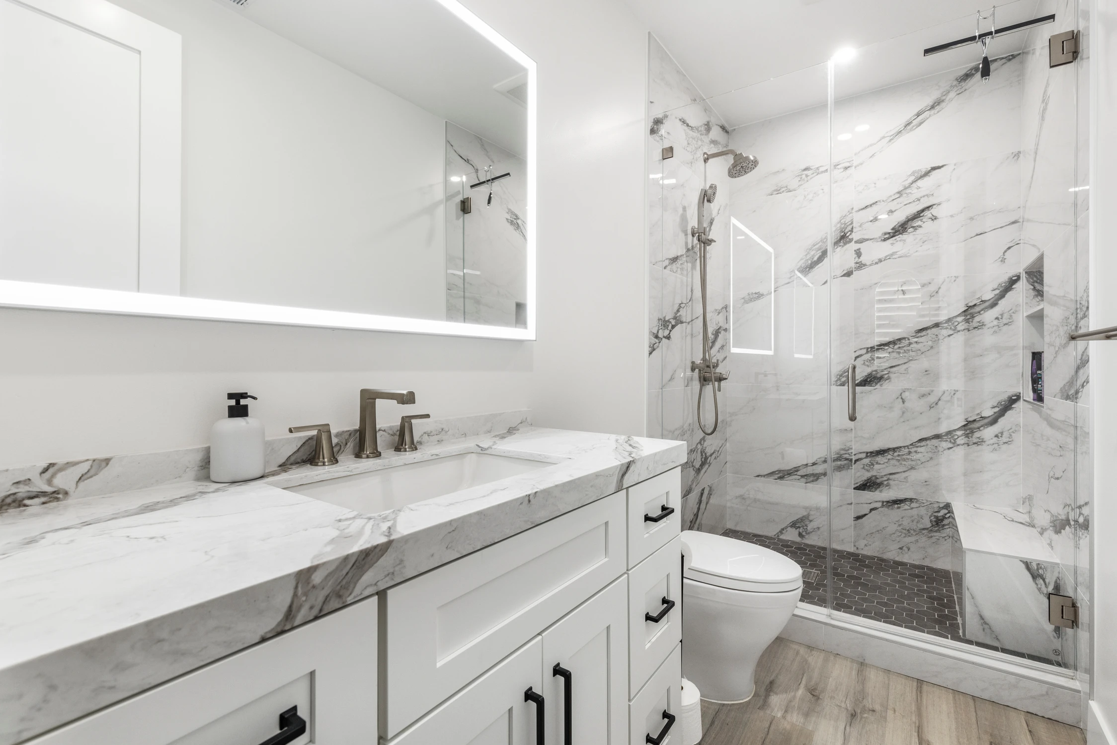 Bathroom vanity with white cabinetry, marble counter, and glass shower