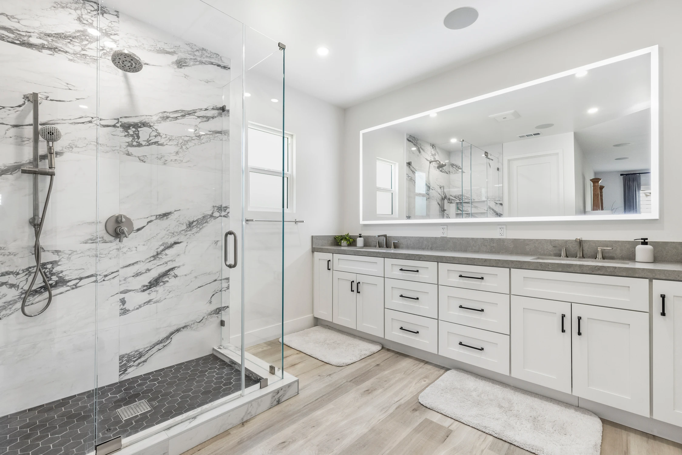 Bathroom vanity with white counter, marble-look tile, and glass shower