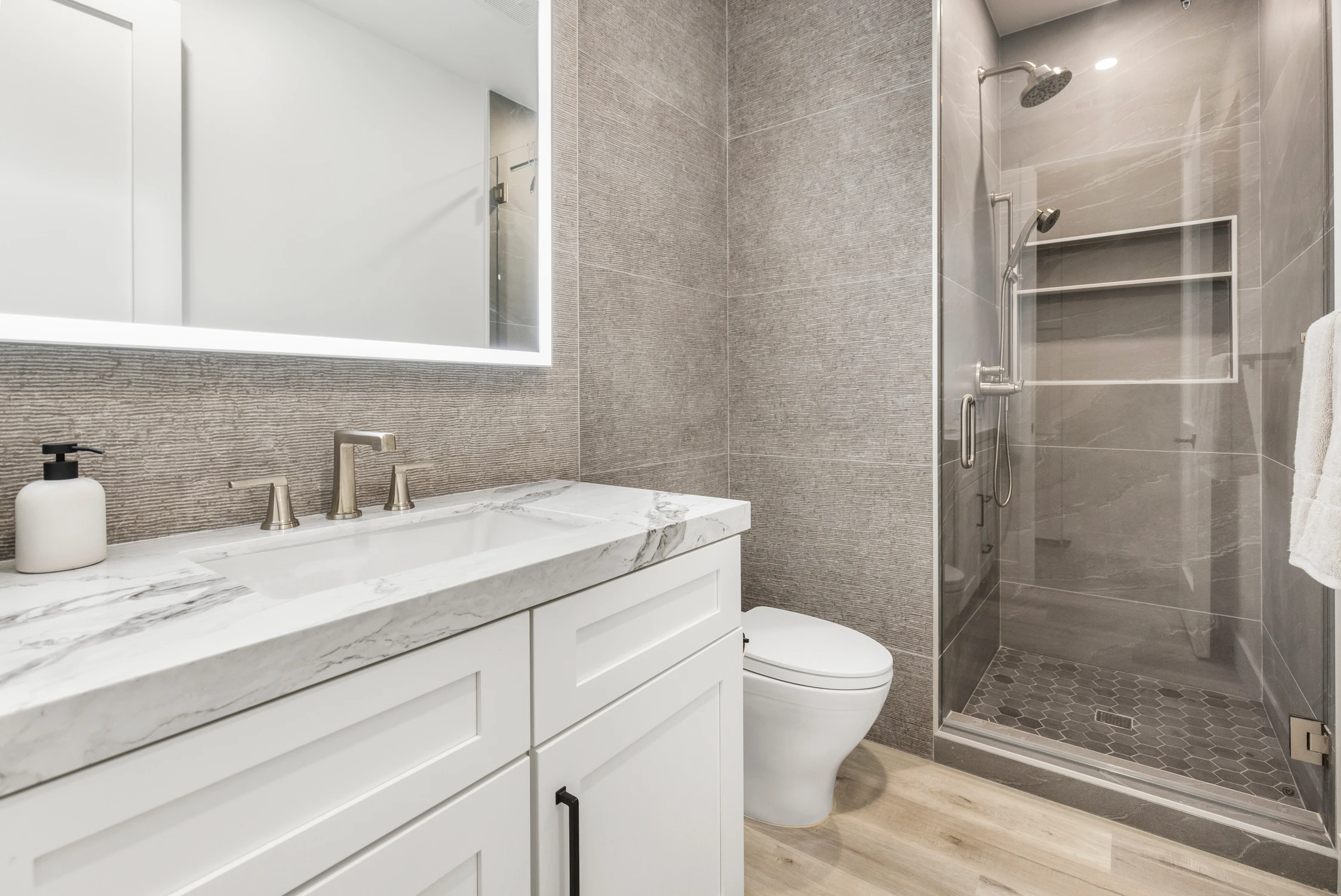 Bathroom vanity with white drawers, gray tile shower, and large mirror
