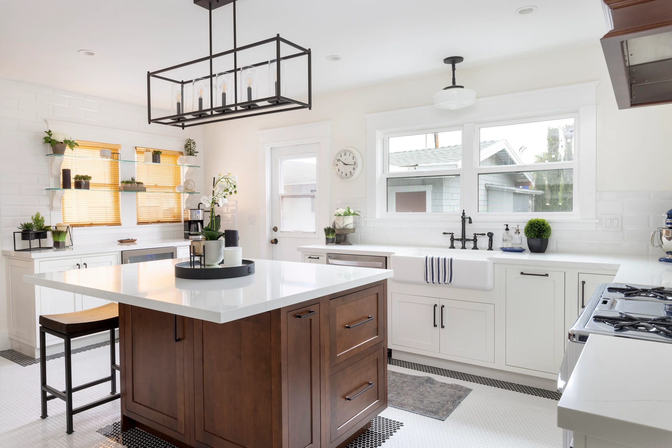 Kitchen island with wood stools, white cabinetry, and open wall shelves