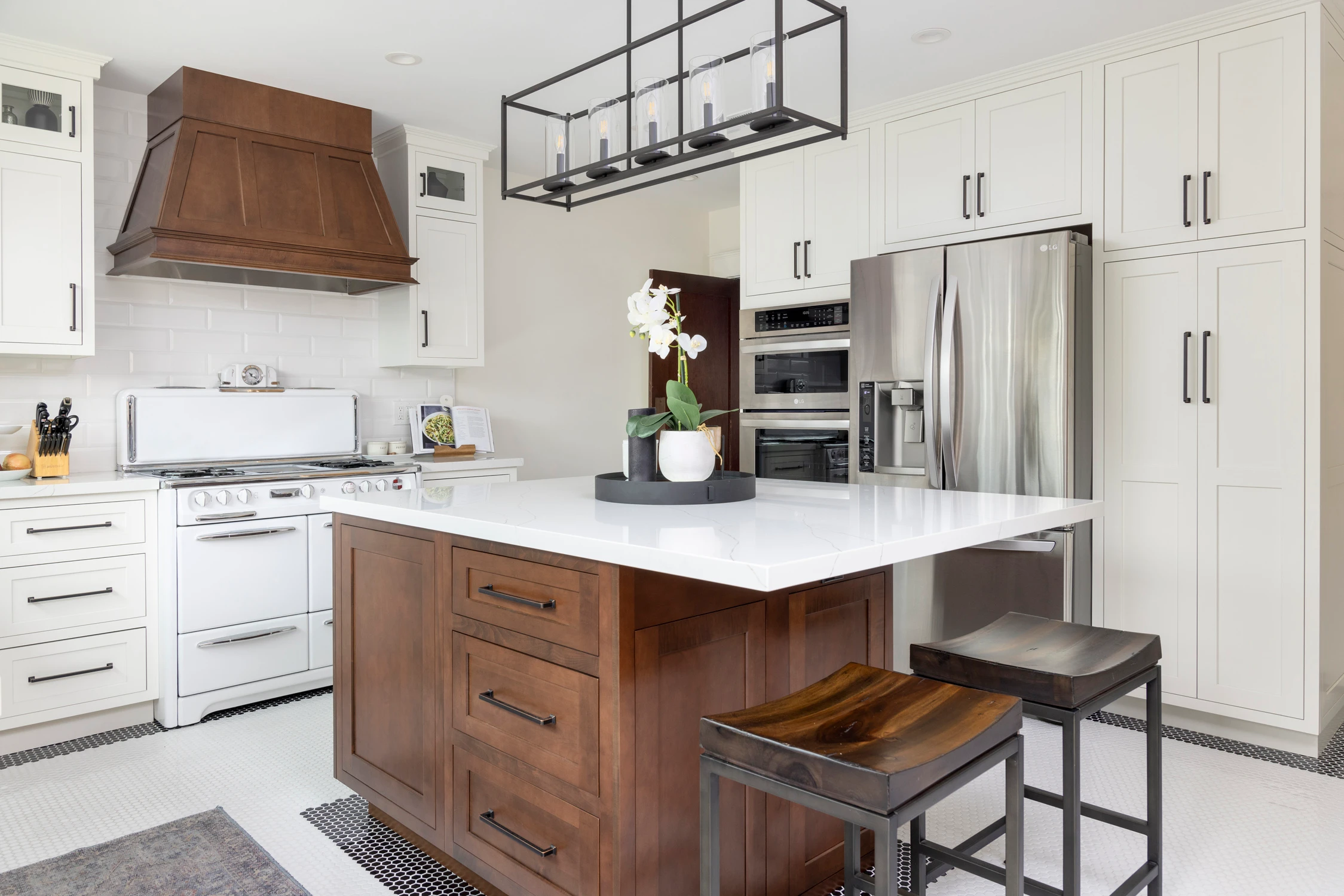 Walnut kitchen island beside white cabinetry and stainless refrigerator
