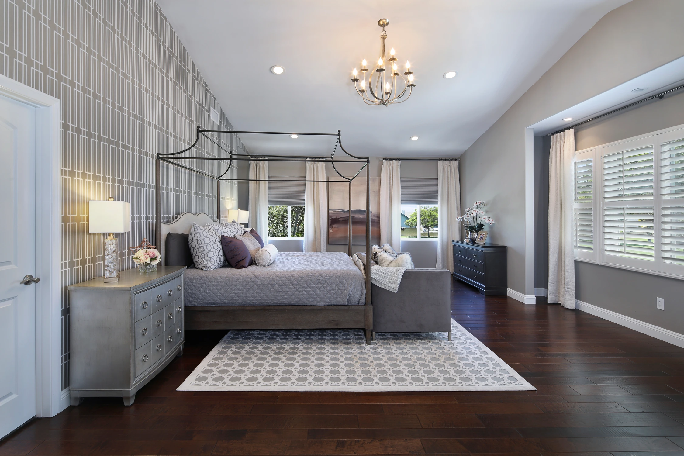 Master bedroom with dark metal canopy bed and patterned accent wall