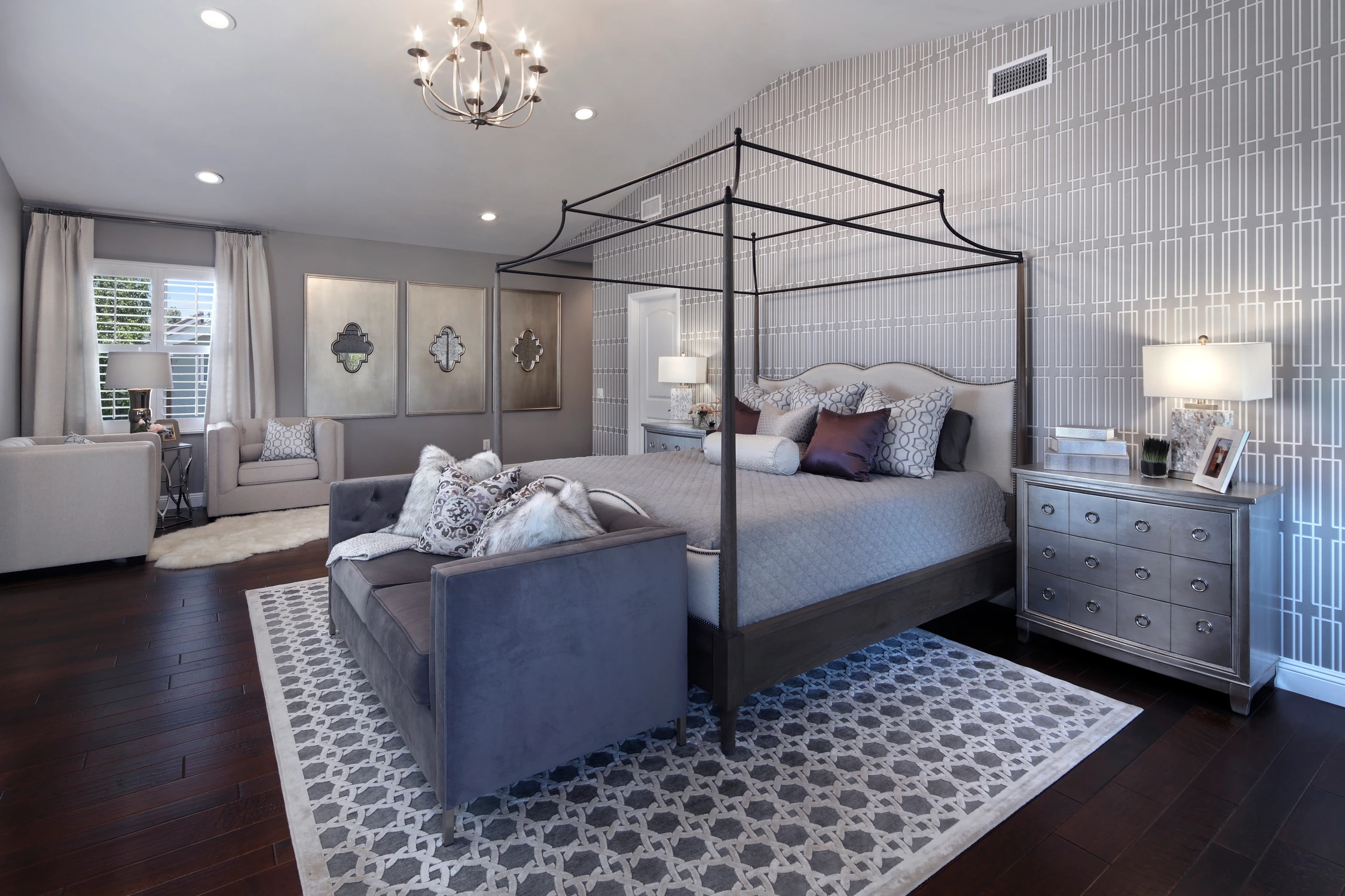 Master bedroom with dark canopy bed, gray loveseat, and patterned rug