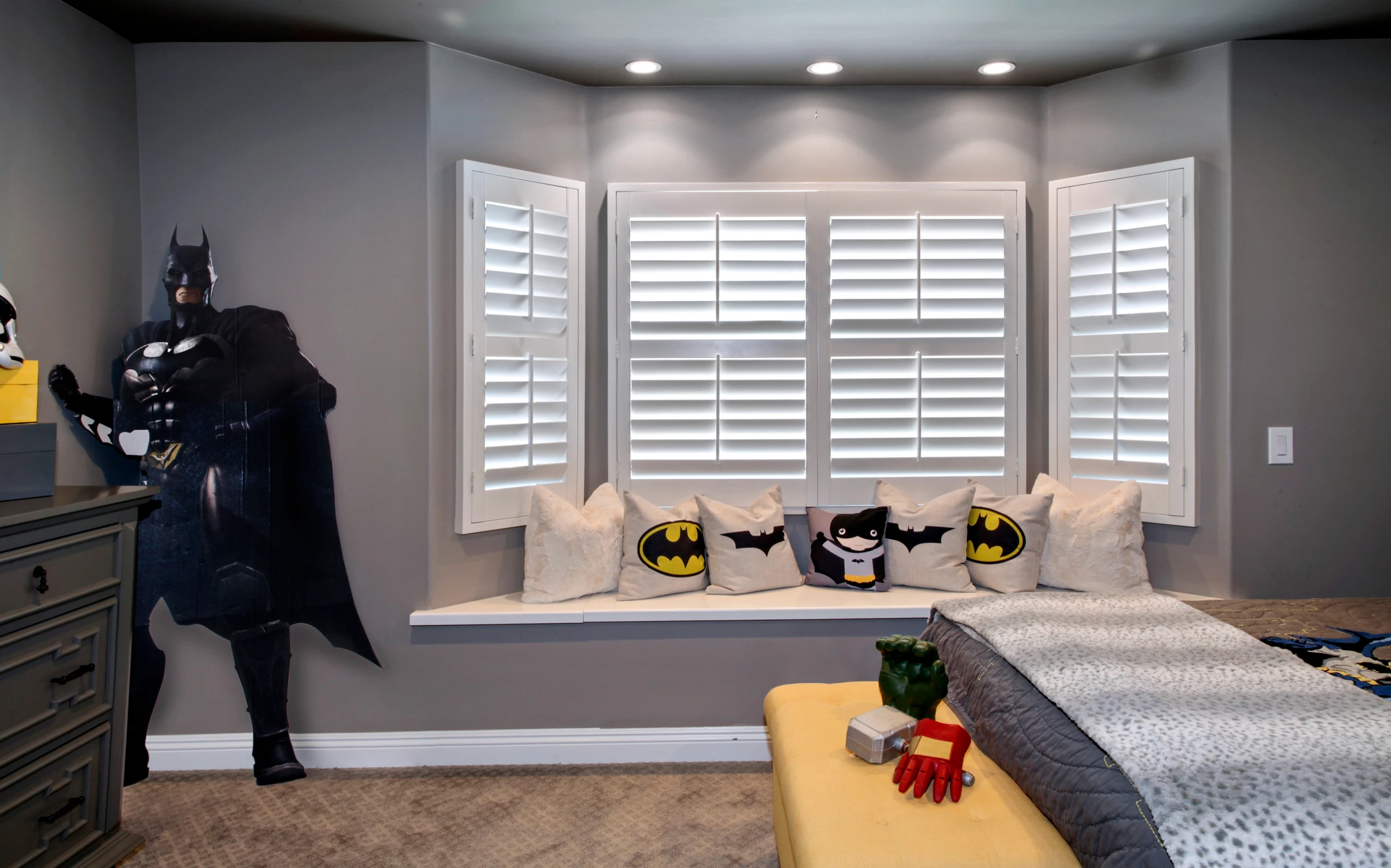 Children's bedroom window seat with themed pillows and white shutters
