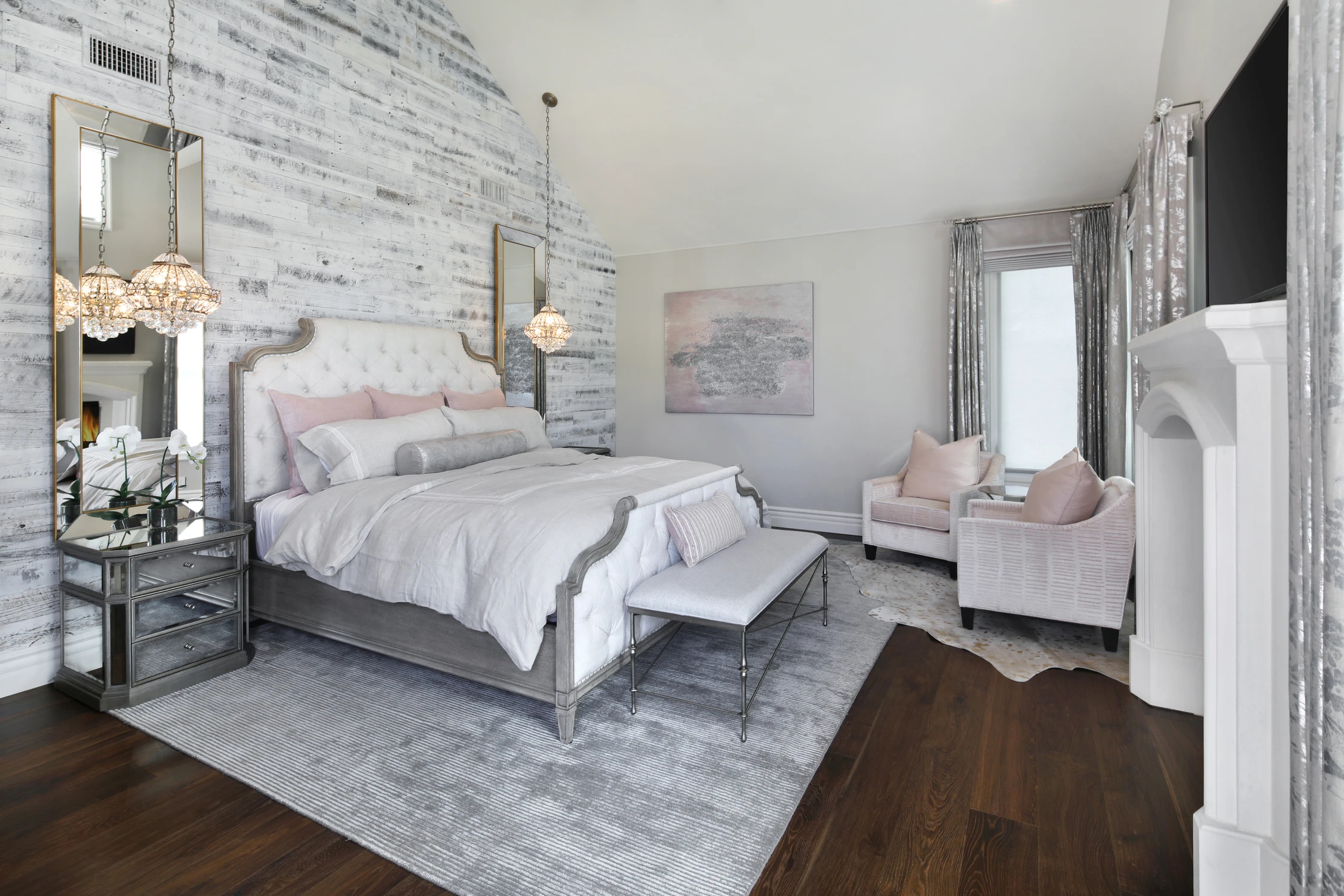Bedroom with pale upholstered bed, whitewashed brick wall, and pink chairs