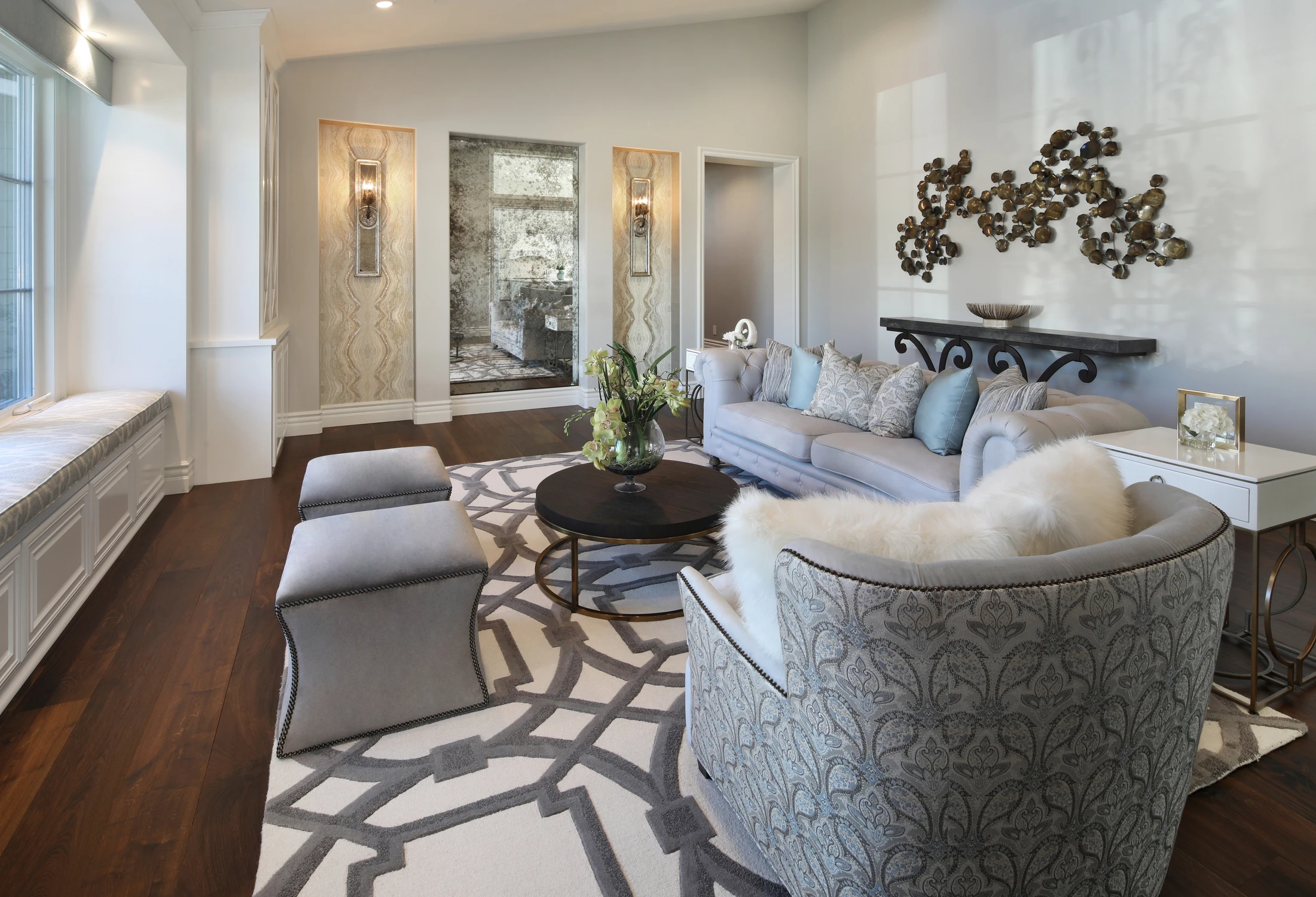 Formal living room with pale sofa, metal wall sculpture, and patterned rug