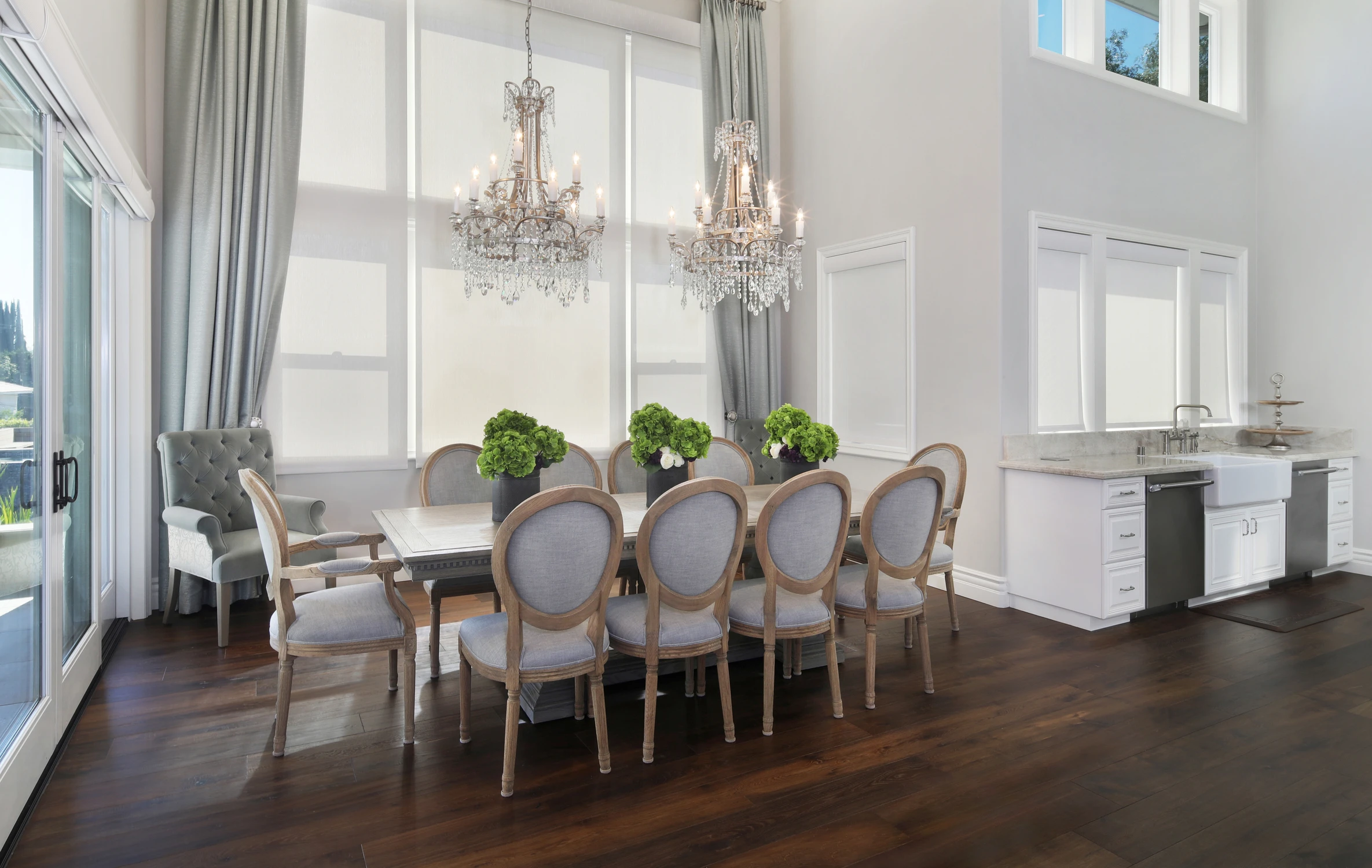Dining area with oval back chairs, white kitchen, and crystal chandelier